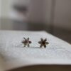 Daisy stud earrings on an old book. The studs are silver for a little bit of rose gold in the middle.